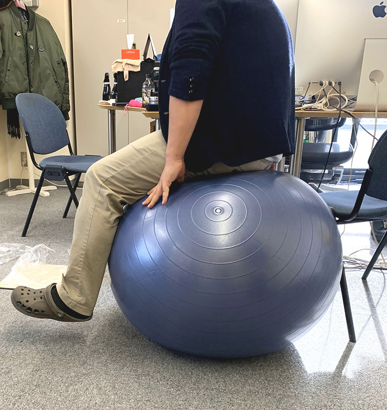 イデアシーディー社内でバランスボールに乗っている男性社員
