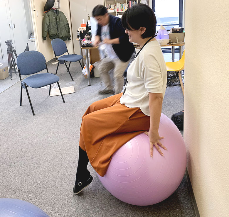 バランスボールに乗る女性社員